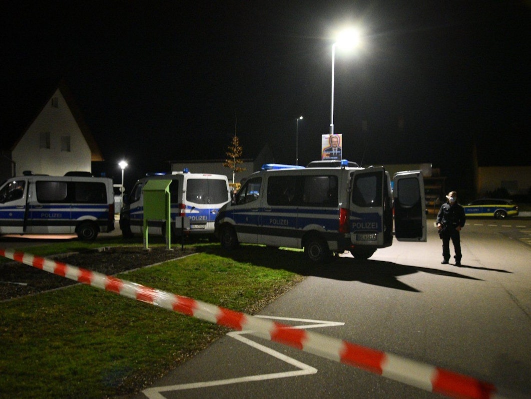 Polizeifahrzeuge in der Nacht vor einem Haus.