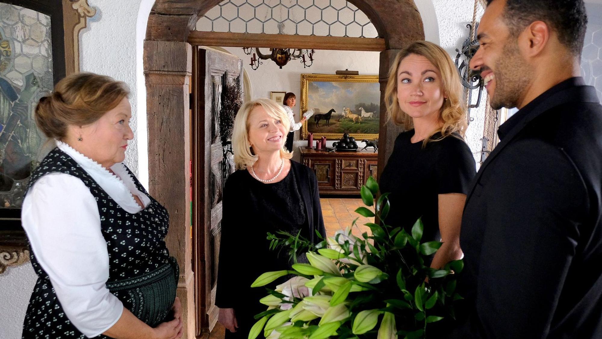 Vier Menschen (drei Frauen und ein Mann) stehen sich gegenüber und lächeln sich an.