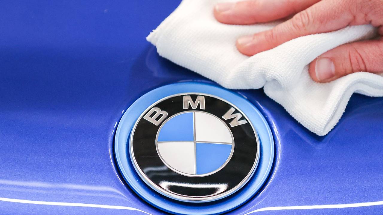 Ein Mitarbeiter von BMW poliert mit einem Tuch das Logo von einem BMW i8.