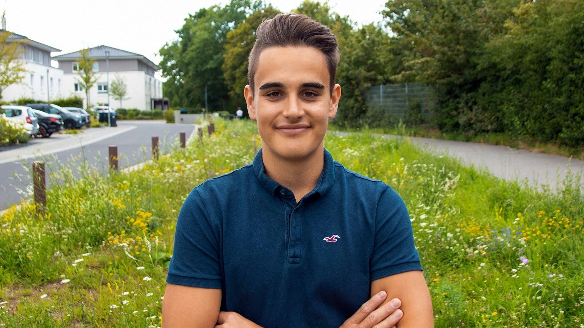 Dario Schramm steht vor einer Wiese und verschränkt die Arme.