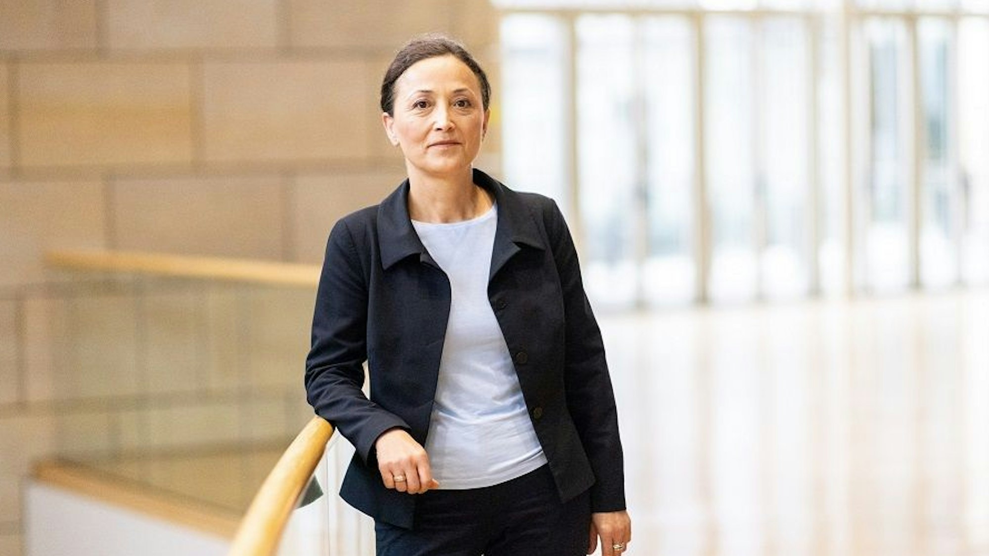 Ayla Celik lehnt an einem Treppengeländer und lächelt in die Kamera.