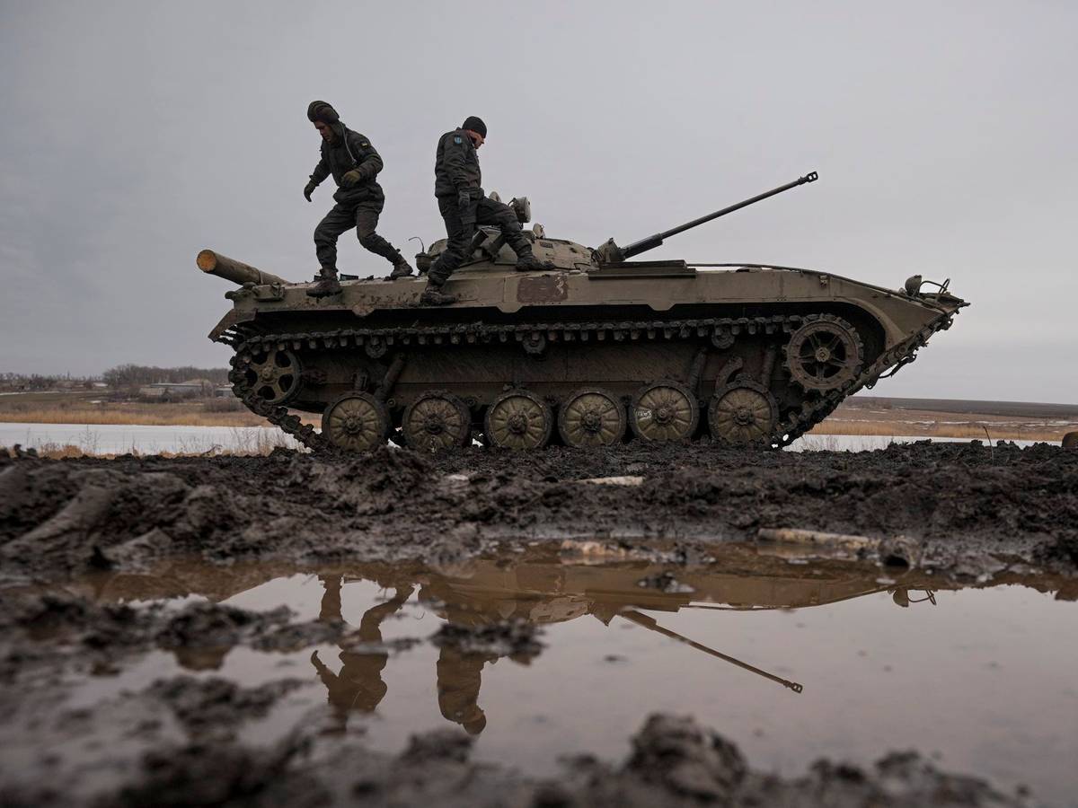 Zwei ukrainische Soldaten stehen während einer Schießübung am 10. Februar auf einem Panzer, der auf einem Feld steht.