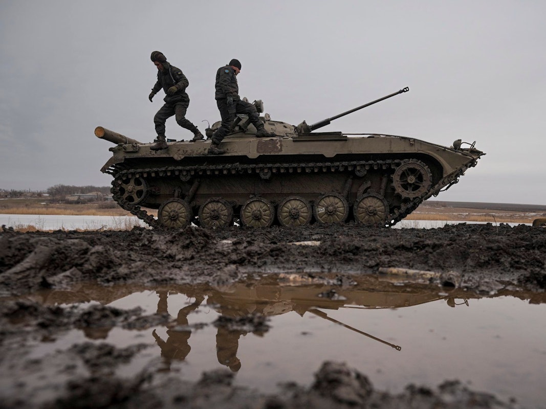 Zwei ukrainische Soldaten stehen während einer Schießübung am 10. Februar auf einem Panzer, der auf einem Feld steht.