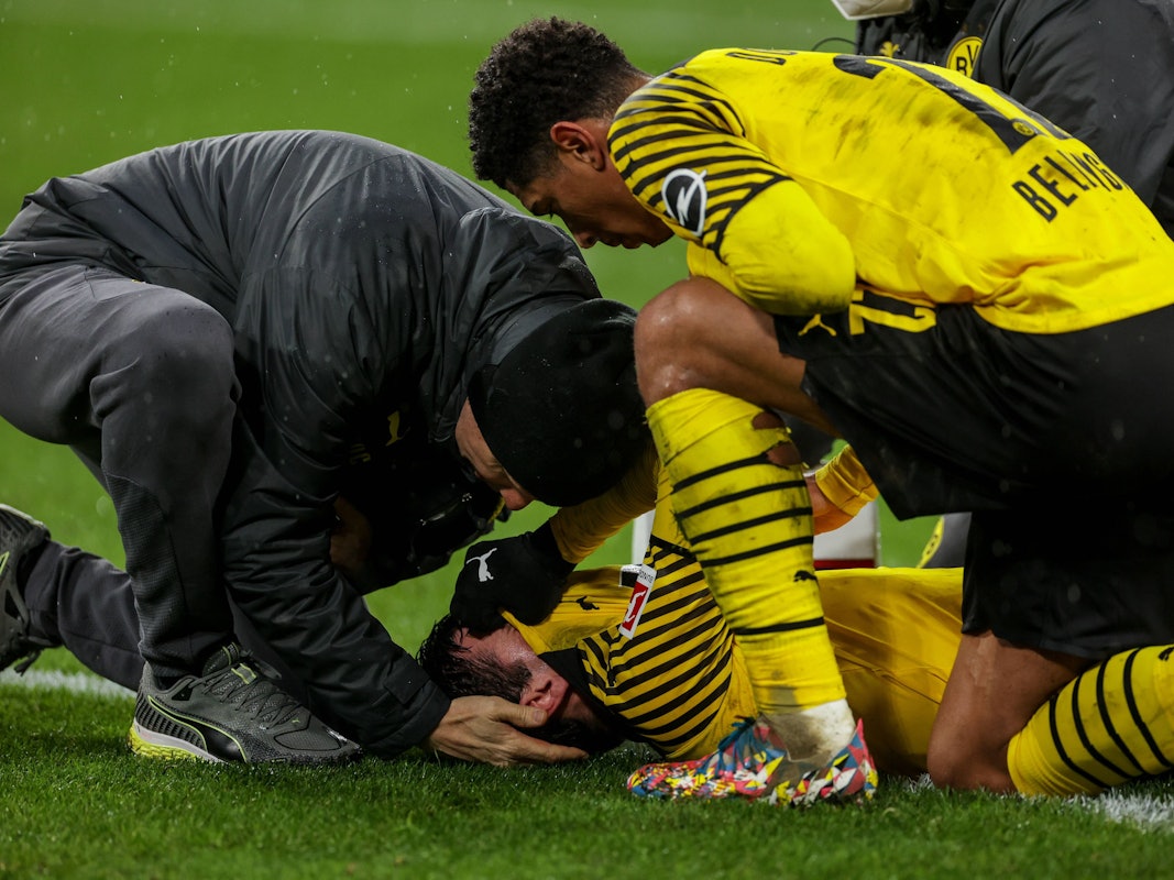 Jude Bellingham kniet auf dem Rasen neben dem verletzten Giovanni Reyna