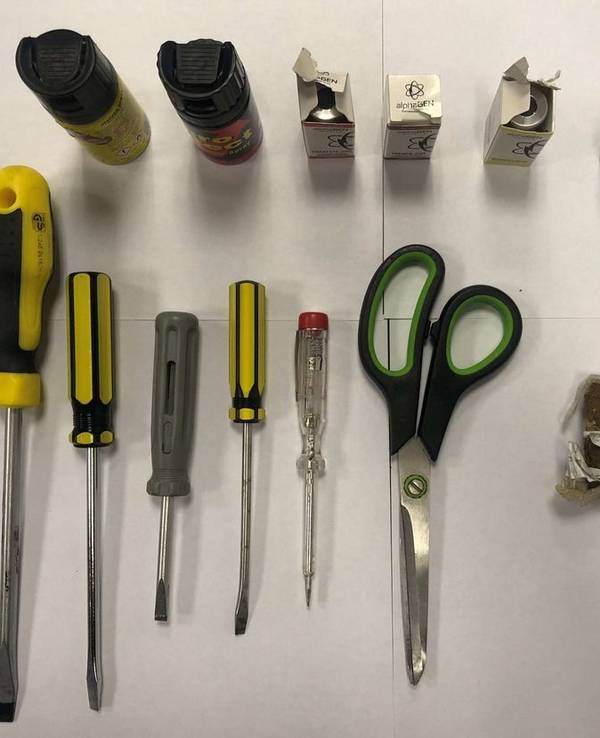 Fünf Schraubenzieher, zwei Tierabwehrsprays und eine Schere liegen auf einem Tisch.