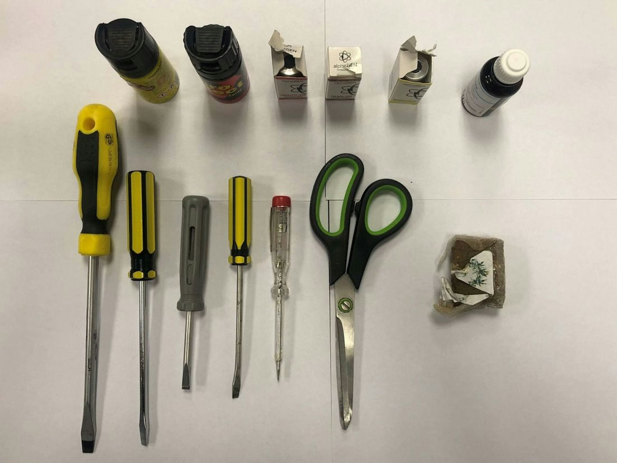 Fünf Schraubenzieher, zwei Tierabwehrsprays und eine Schere liegen auf einem Tisch.