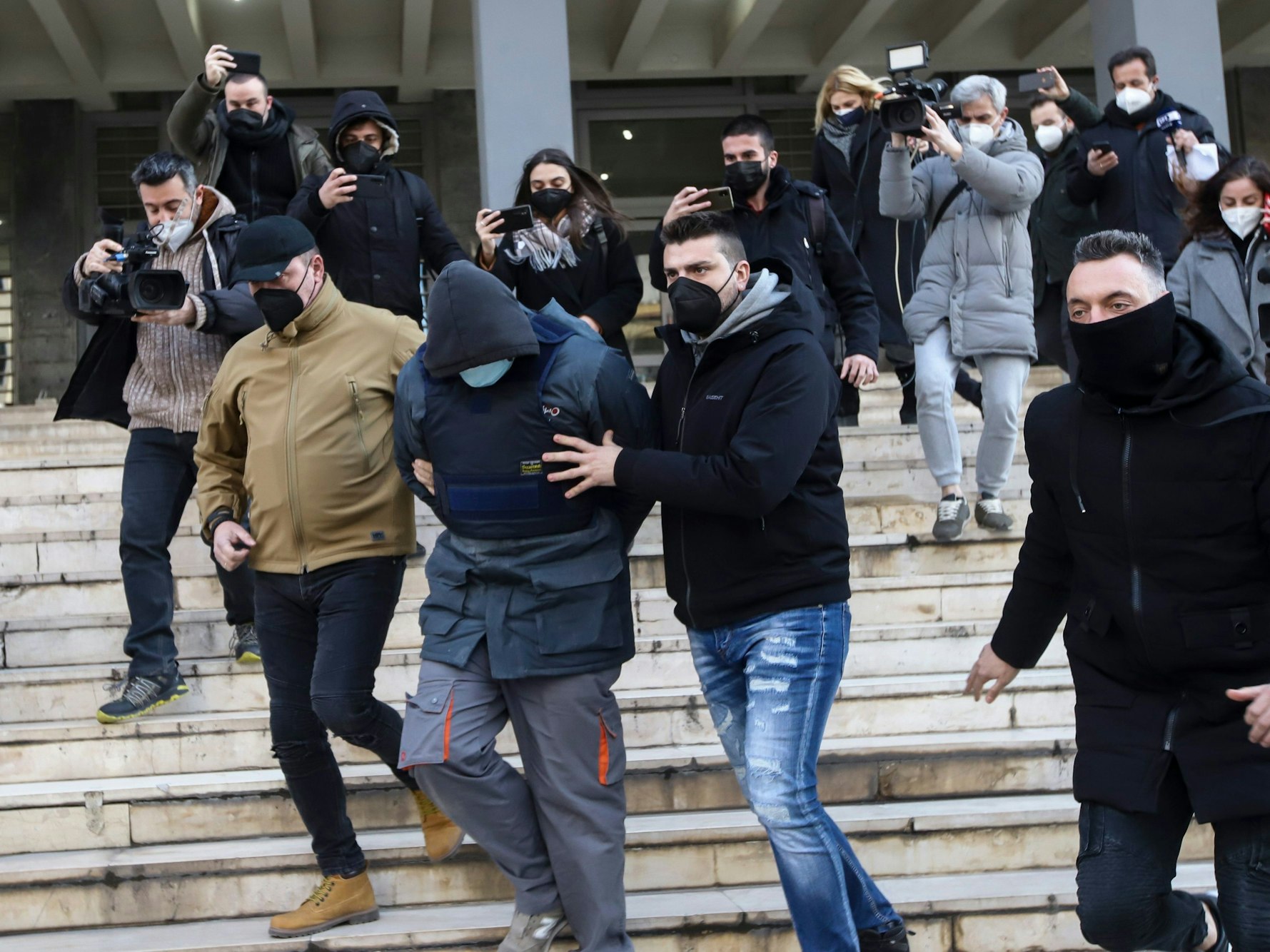 Griechische Polizeibeamte in Zivil begleiten den Tatverdächtigen beim Verlassen des Gerichtsgebäudes in Athen.