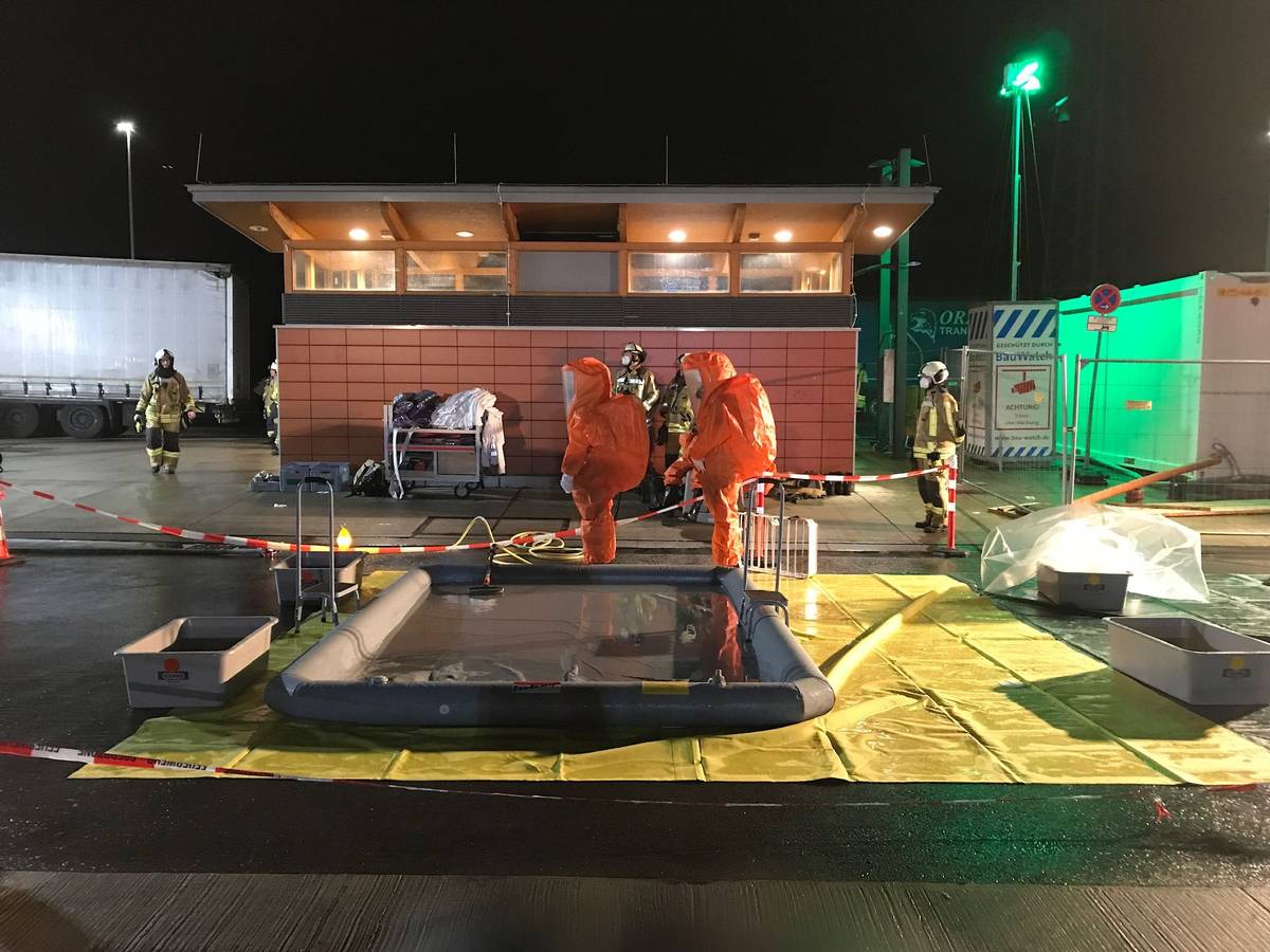 Einsatzkräfte in orangenen Anzügen an einer Raststätte der A2.