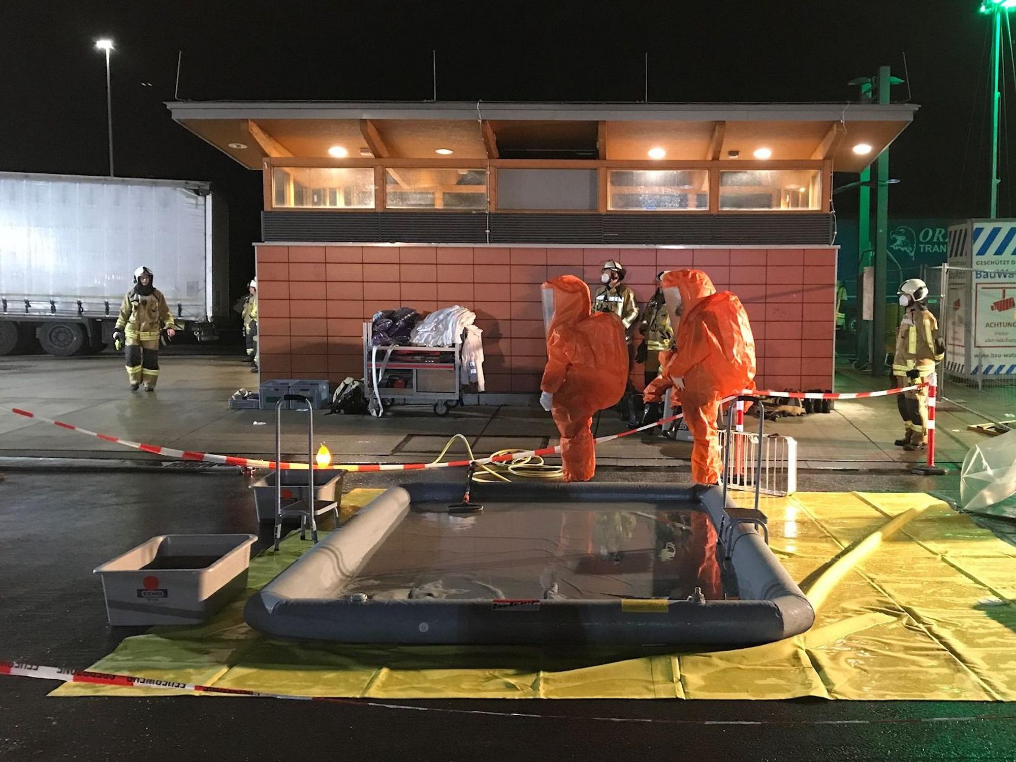 Einsatzkräfte in orangenen Anzügen an einer Raststätte der A2.