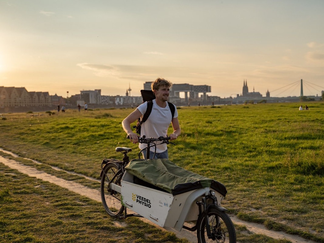Jonas Eiken auf seinem Lastenfahrrad vor dem Dom-Panorama.