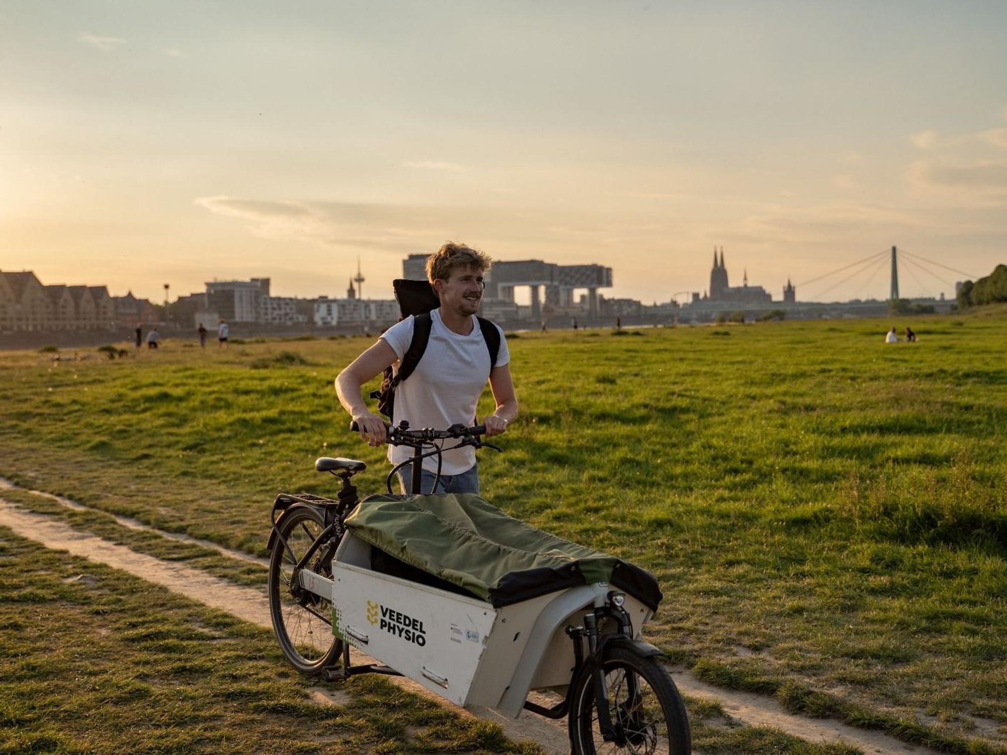 Jonas Eiken auf seinem Lastenfahrrad vor dem Dom-Panorama.