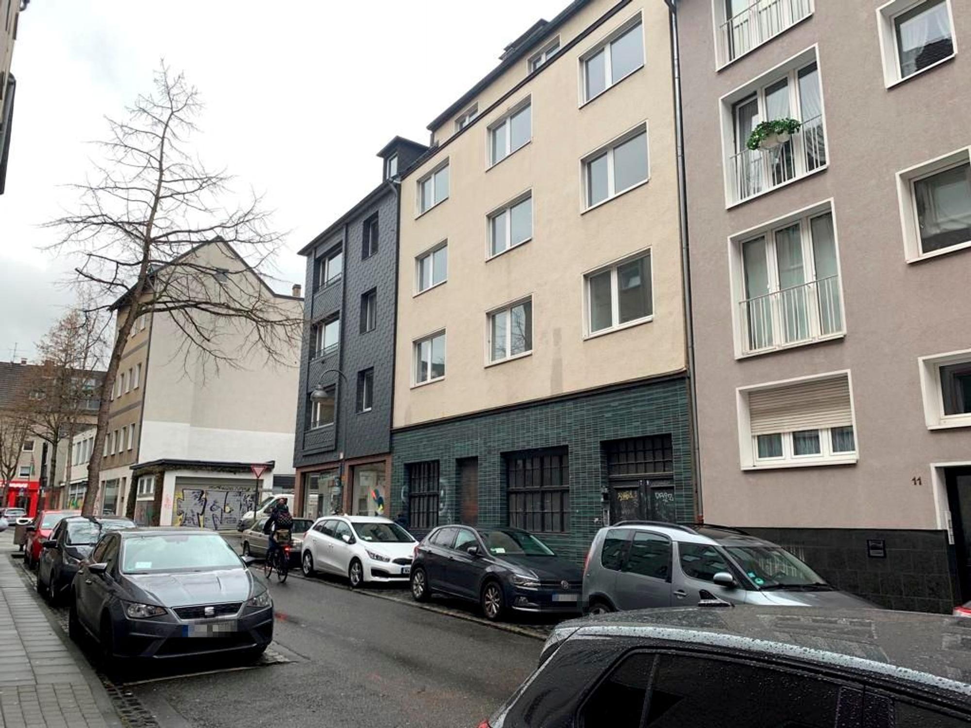 Blick auf eine Straße mit Wohnhäusern und geparkten Autos.