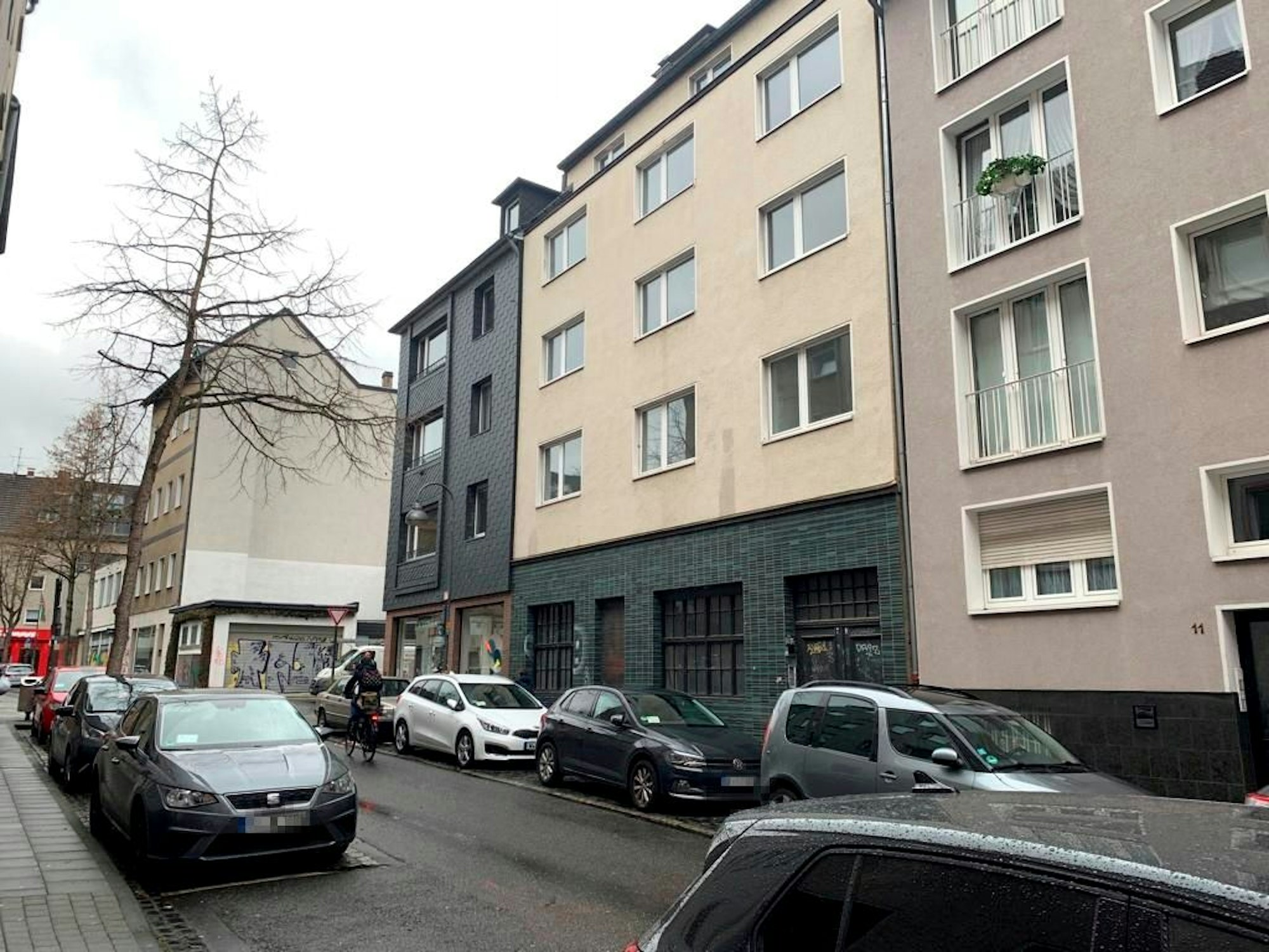 Blick auf eine Straße mit Wohnhäusern und geparkten Autos.