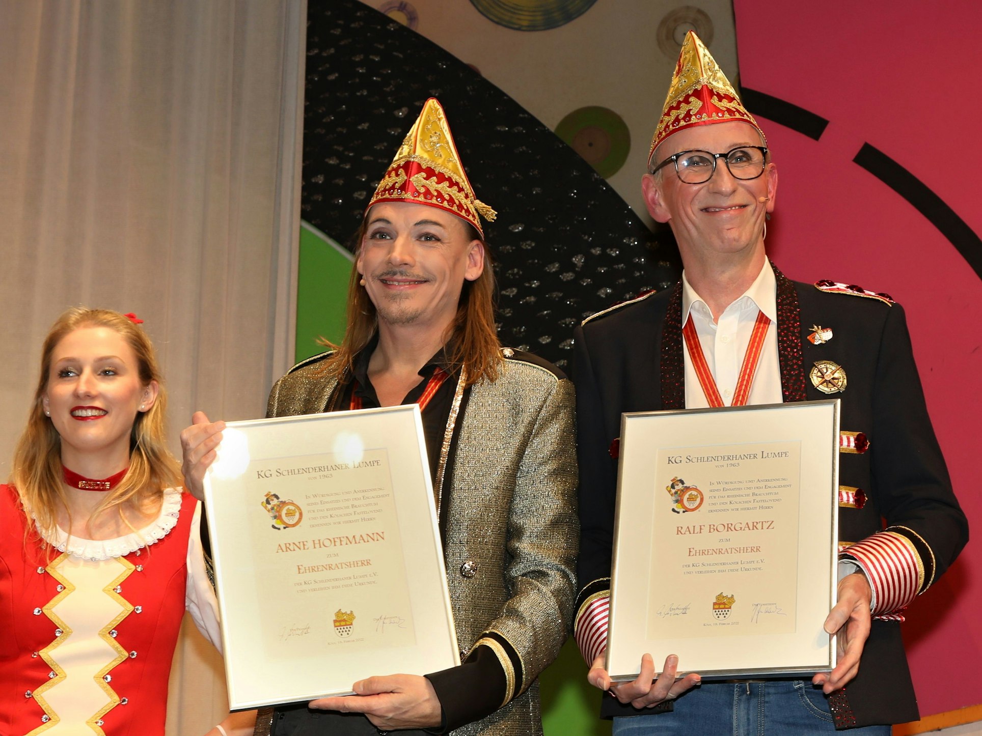 Zwei Männer mit Urkunde lachen in die Kamera.