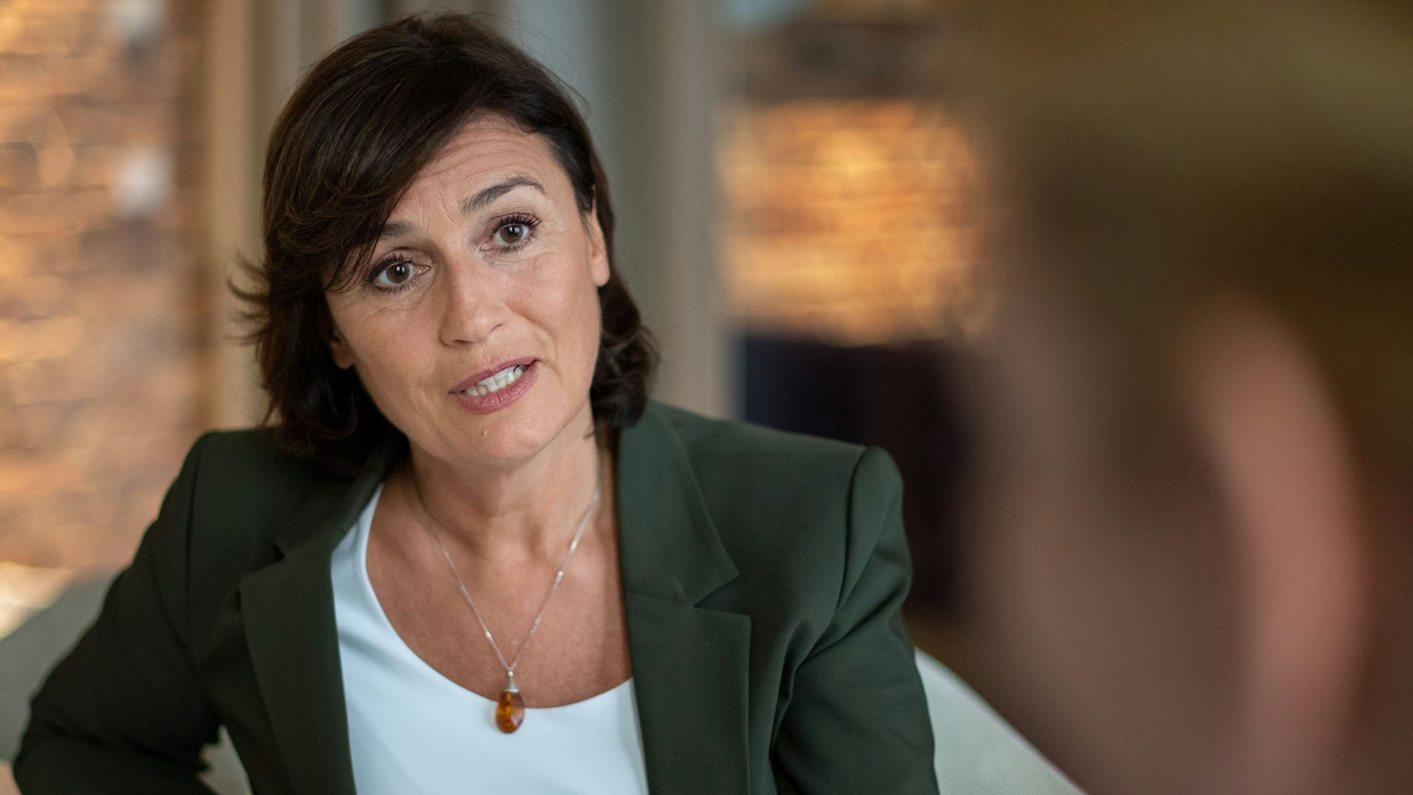 Sandra Maischberger sitzt in einem Studio und stellt sich Interview-Fragen.