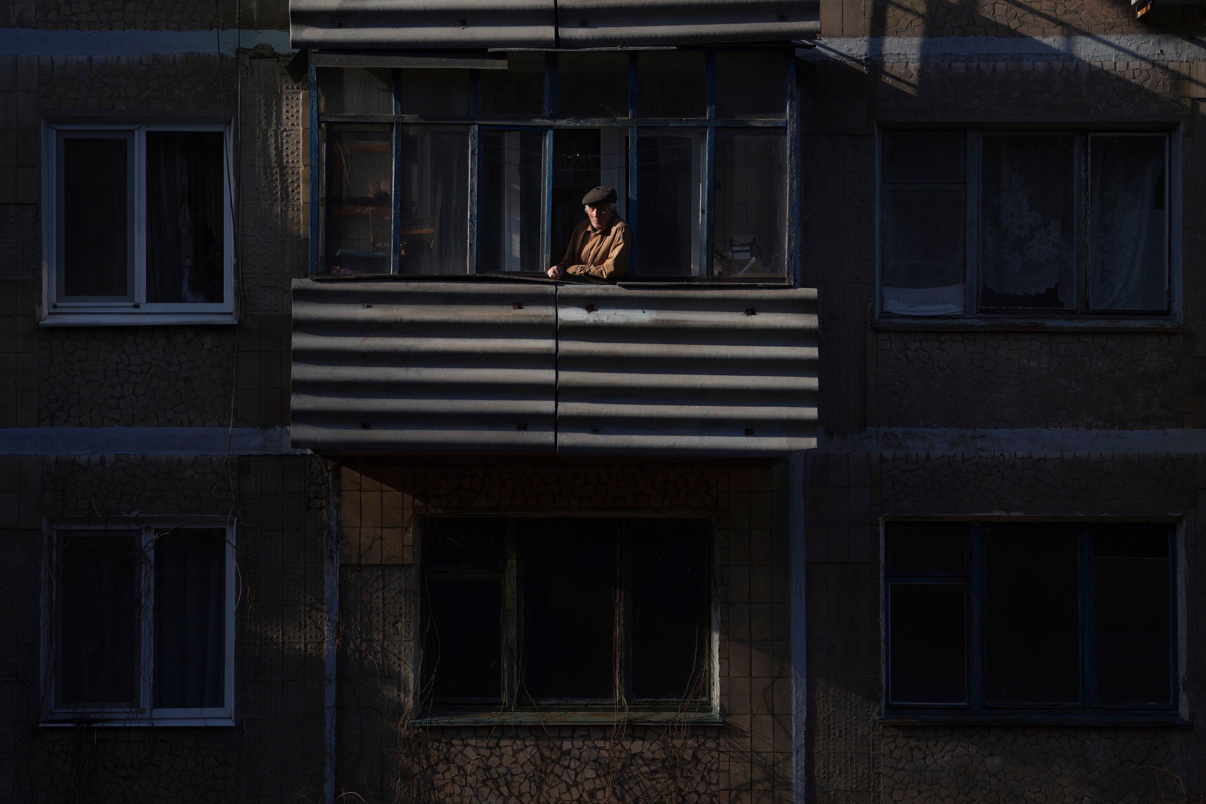 23.02.2022, Ukraine, Novoluhanske: Ein Mann blickt nach einem Artilleriebeschuss bei Sonnenuntergang von einem Balkon. Die Ukraine rüstet sich für einen Krieg mit Russland. Präsident Selenskyj kündigte eine Teilmobilmachung von Reservisten an. Foto: Evgeniy Maloletka/AP/dpa +++ dpa-Bildfunk +++