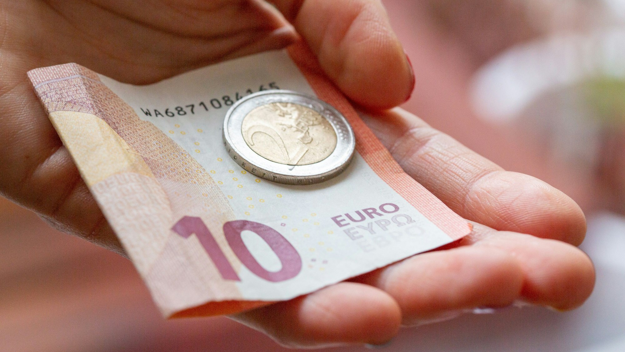 Eine Person hält 12 Euro in der Hand. Das Bundeskabinett hat die geplante Erhöhung des Mindestlohns auf 12 Euro auf den Weg gebracht.