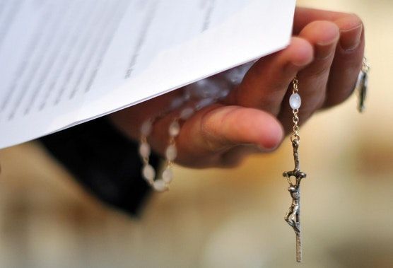 Christliches Kreuz in der Hand eines Priesters.