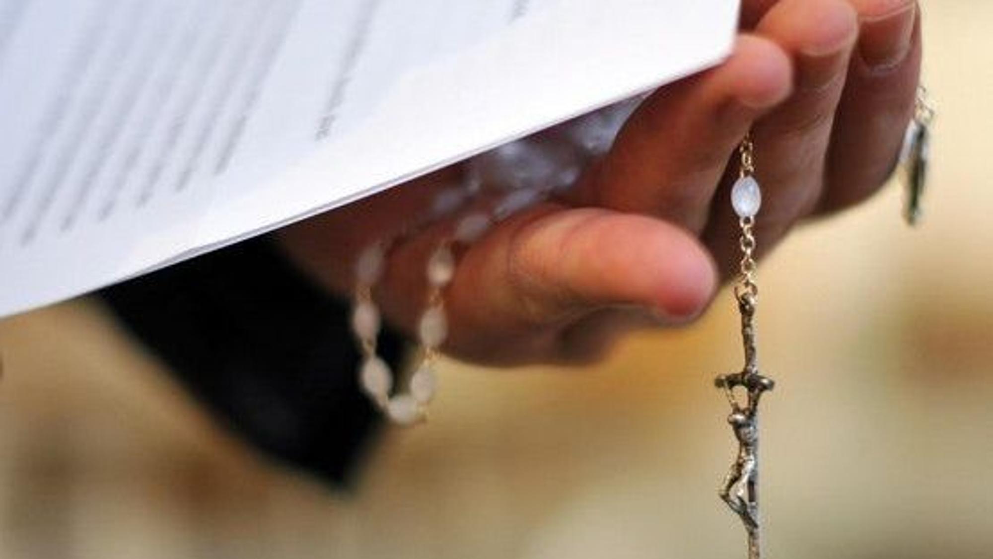 Christliches Kreuz in der Hand eines Priesters.