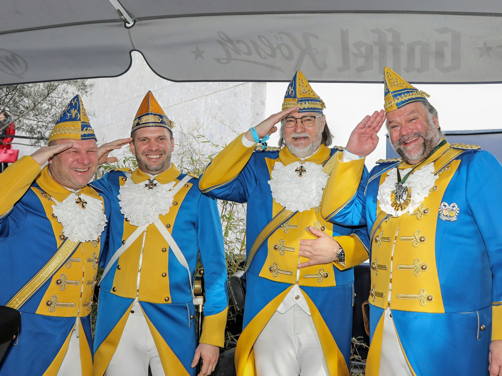 Vier Männer in Uniform grüßen in die Kamera.