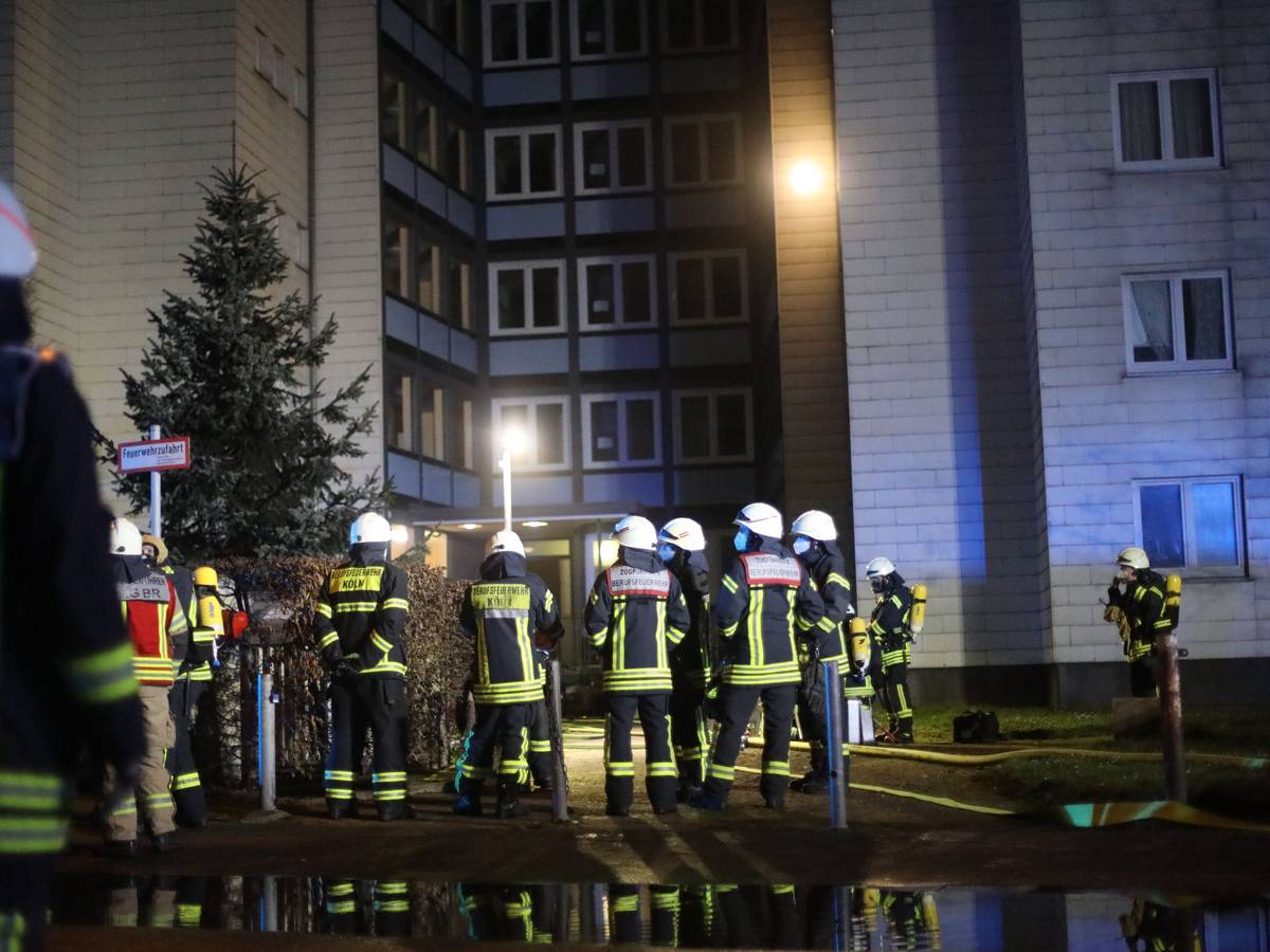 Einsatzkräfte der Feuerwehr vor einem Wohnhaus.