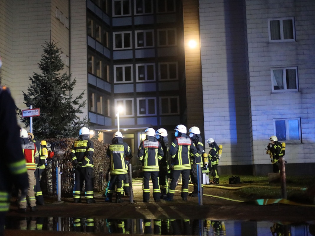 Einsatzkräfte der Feuerwehr vor einem Wohnhaus.