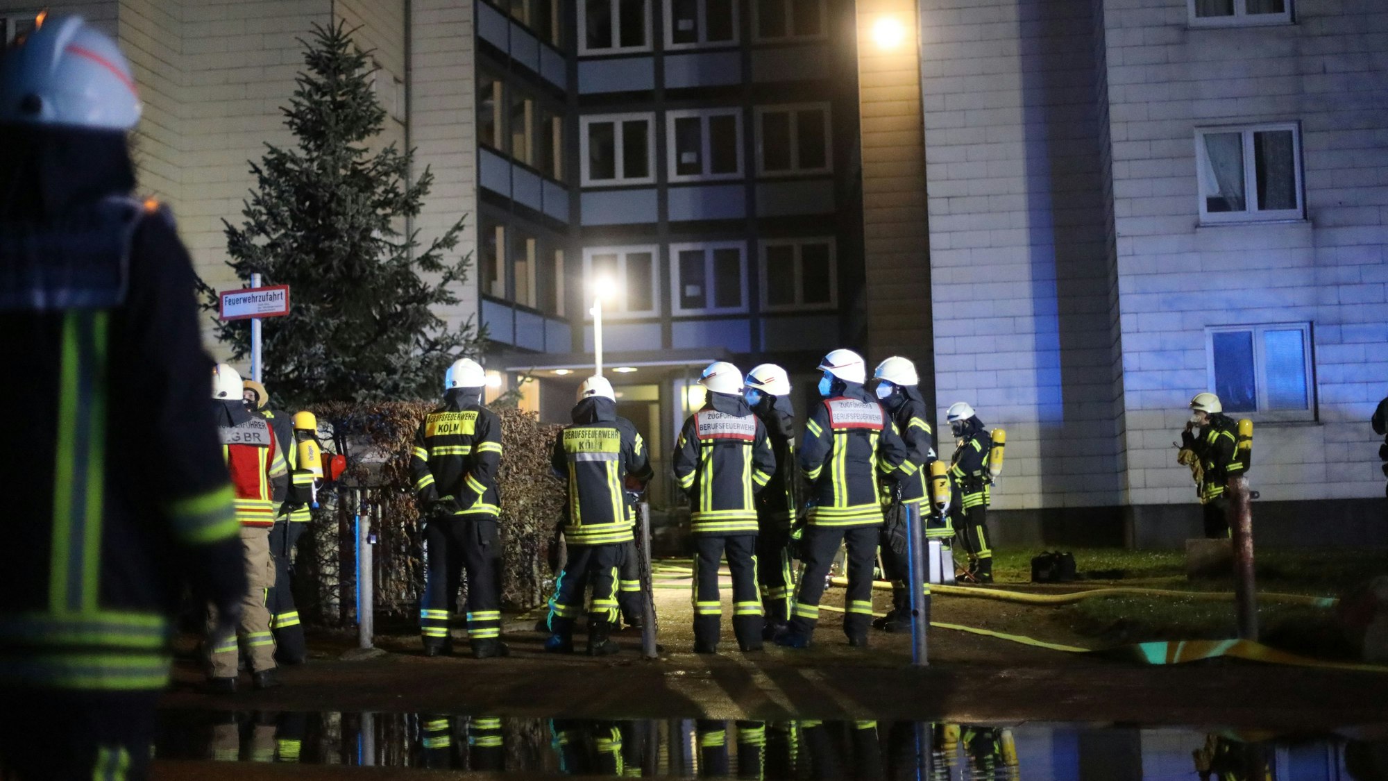 Einsatzkräfte der Feuerwehr vor einem Wohnhaus.