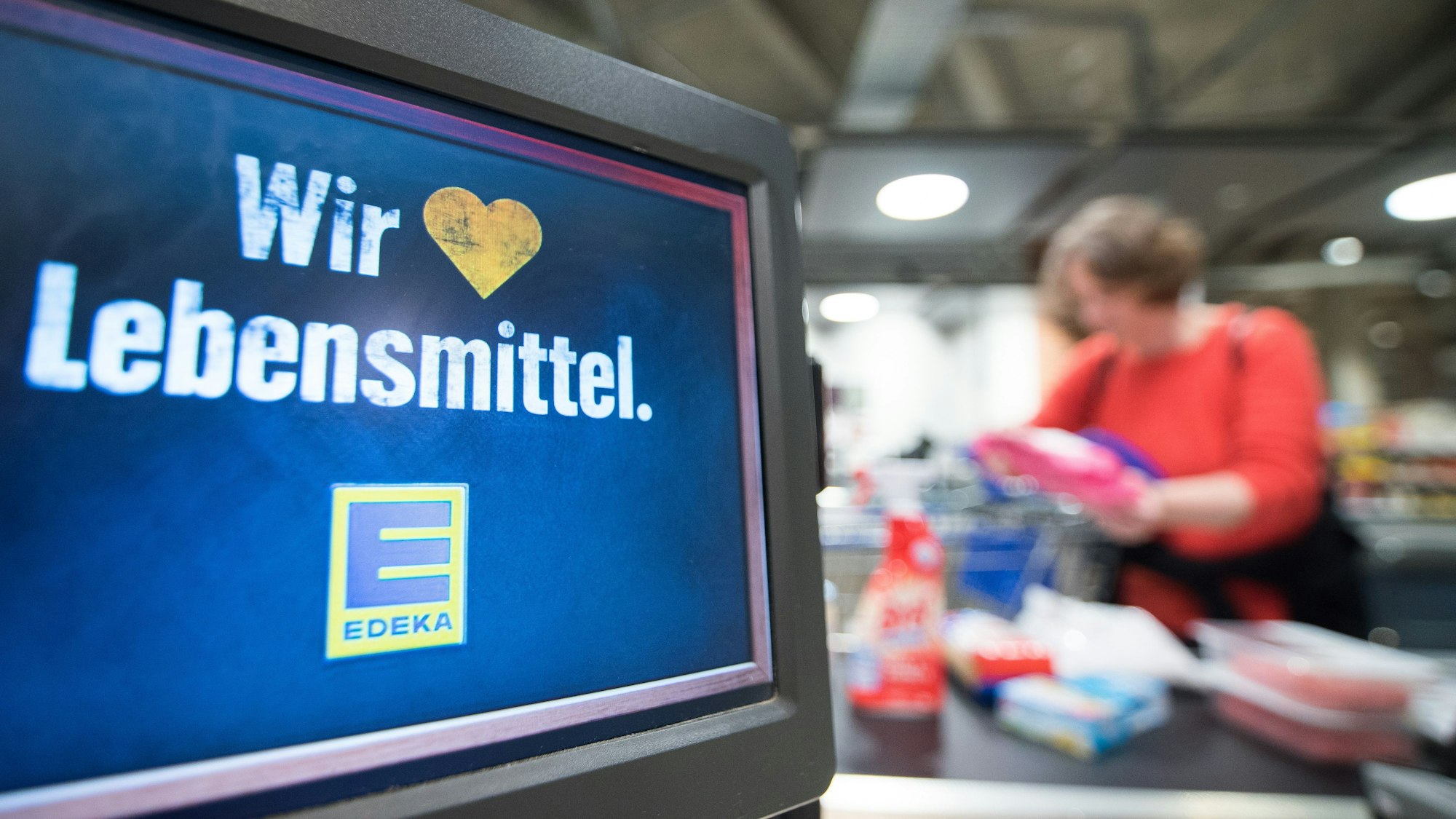 Eine Kundin räumt am 11.05.2015 in Hamburg in einem Edeka-Markt an der Kasse ihren Einkauf auf das Laufband. Der genossenschaftliche Edeka-Verbund hat seine führende Position im Handel mit Lebensmitteln ausgebaut. Foto: Daniel Bockwoldt/dpa (zu dpa "Edeka baut führende Position im deutschen Lebensmittelhandel aus" vom 11.05.2015) ++ +++ dpa-Bildfunk +++