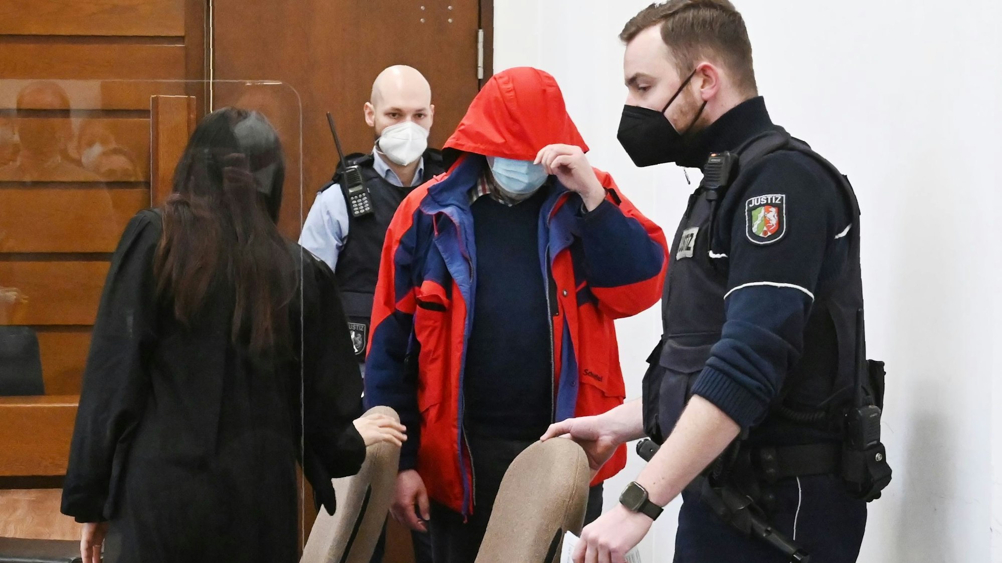 Angeklagte wird von Polizei in einen Gerichtssaal geführt.