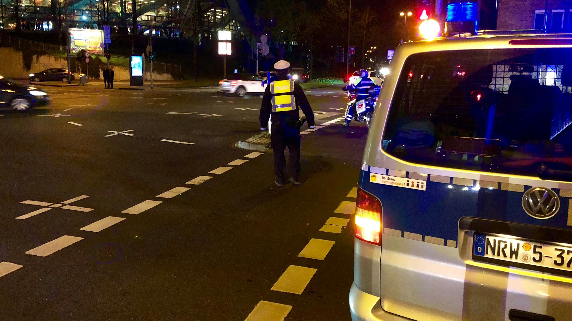 Ein Polizeifahrzeug und ein Polizist stehen auf einer Straße.