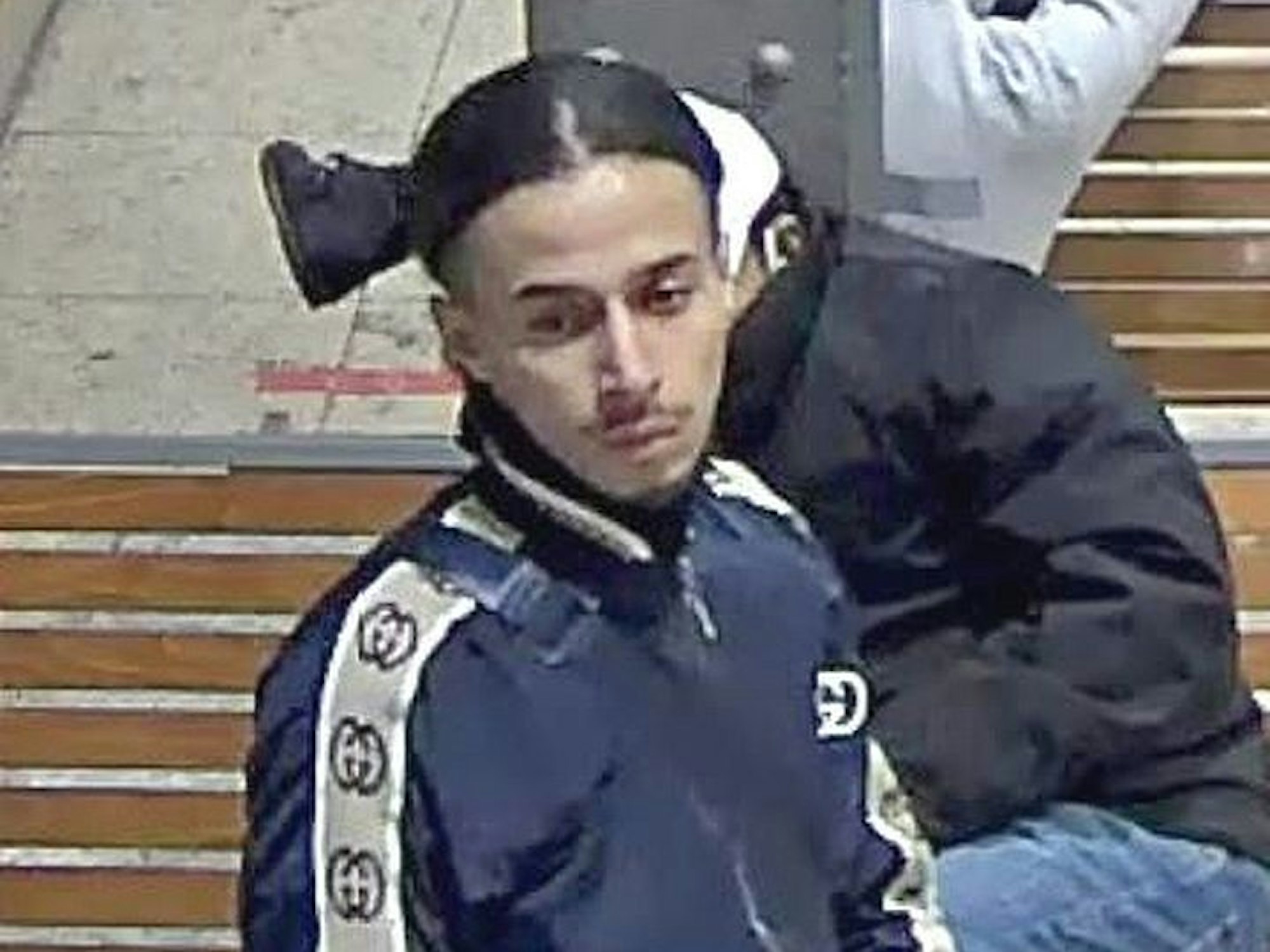 Mann in Gucci-Jacke ist auf Fahndungsfoto zu sehen.
