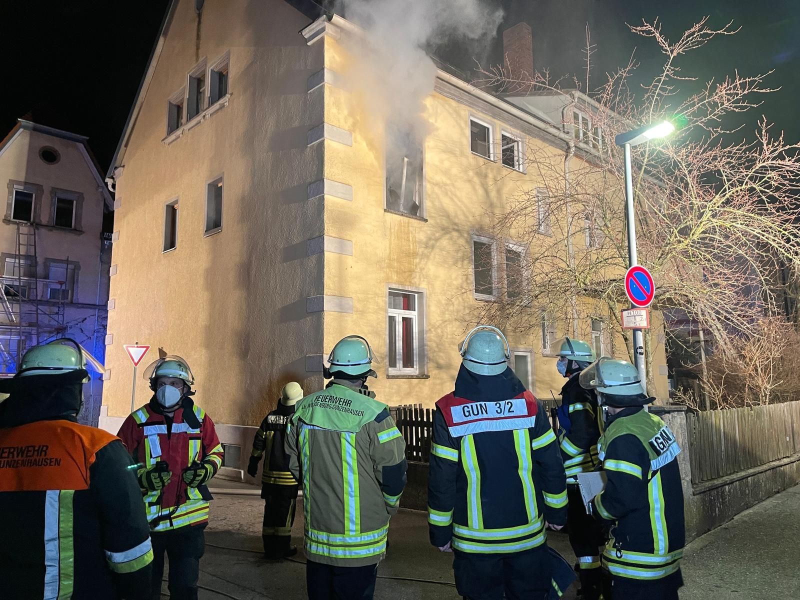 Einsatzkräfte der Feuerwehr stehen am 17.03.2021 vor einem Gebäude in Gunzenhausen aus dem Feuer aufsteigt.