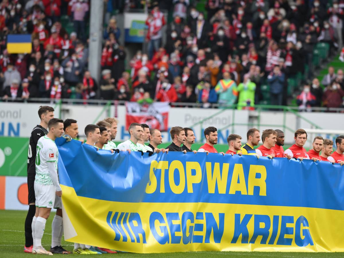 Die Spieler von Greuther Fürth und dem 1. FC Köln halten ein Banner hoch.