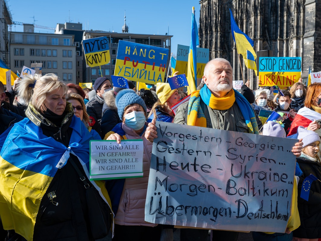 Menschen demonstrieren mit Ukraine-Flaggen gegen den Krieg.