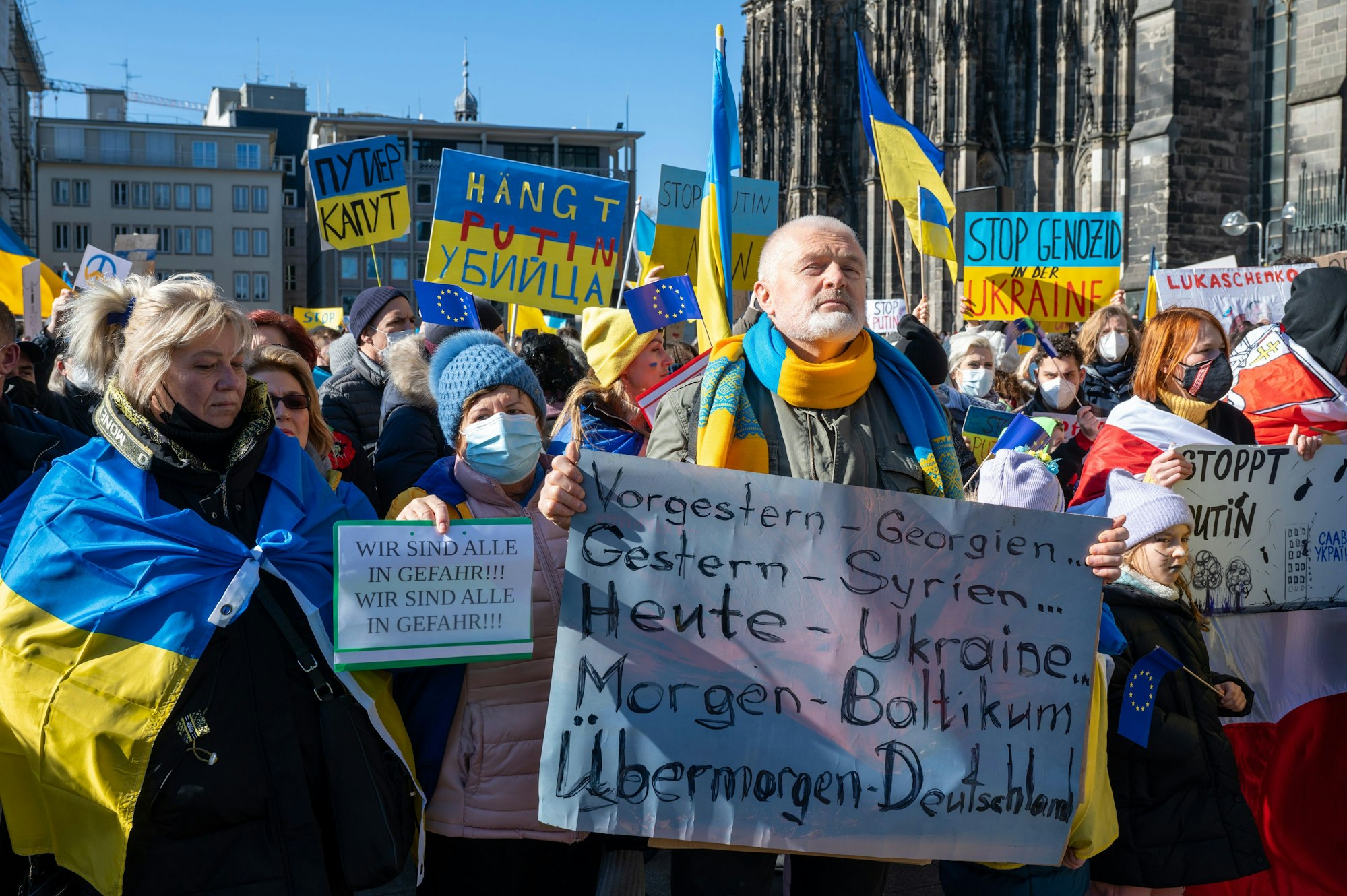Menschen demonstrieren mit Ukraine-Flaggen gegen den Krieg.