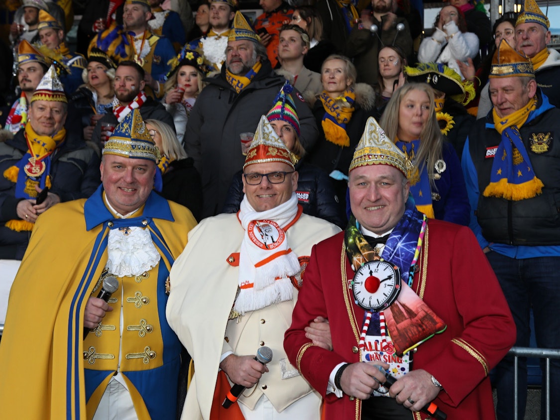 Drei Moderatoren lachen bei Karnevals-Event in die Kamera.