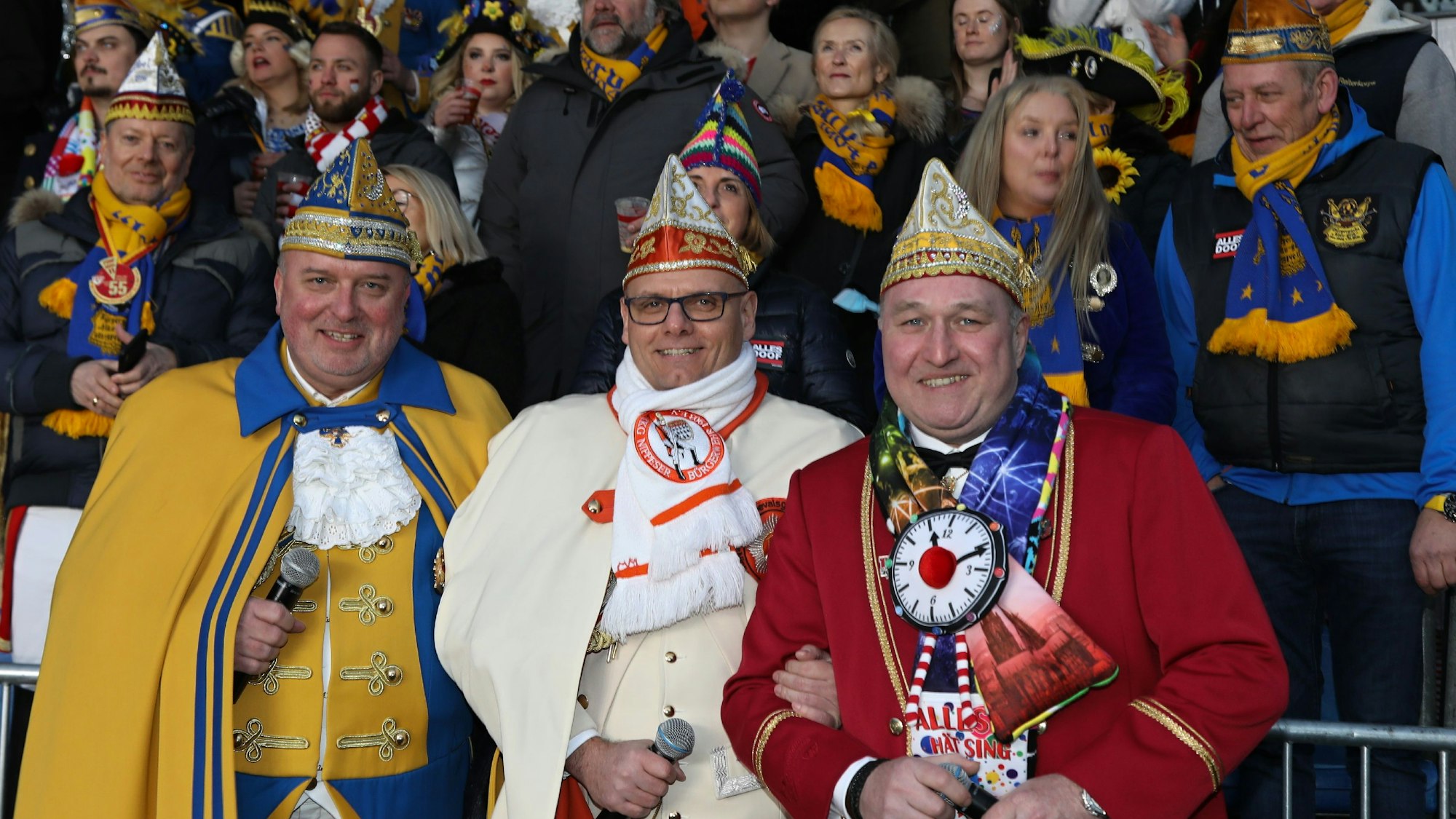 Drei Moderatoren lachen bei Karnevals-Event in die Kamera.