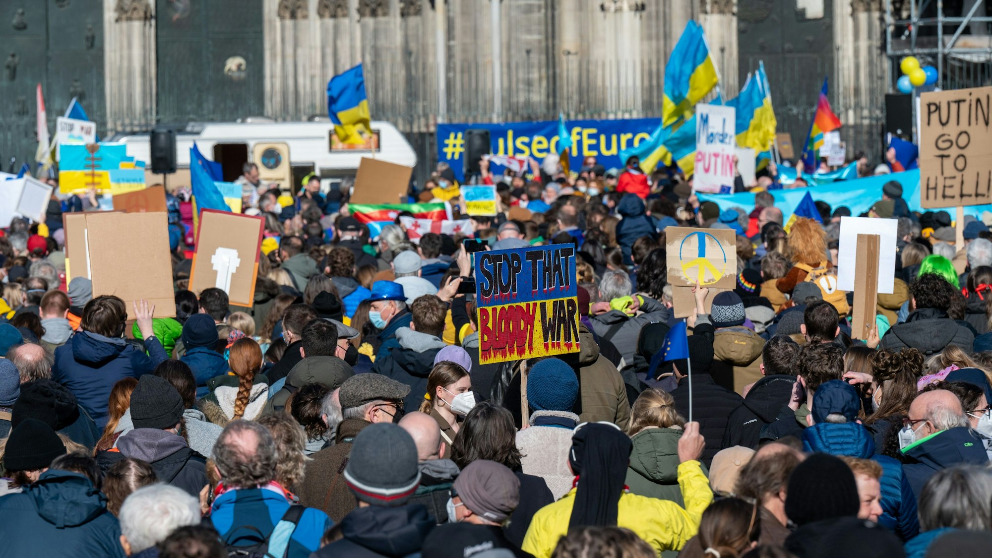 Menschen demonstrieren mit Fahnen der Ukraine gegen den Krieg Russlands.