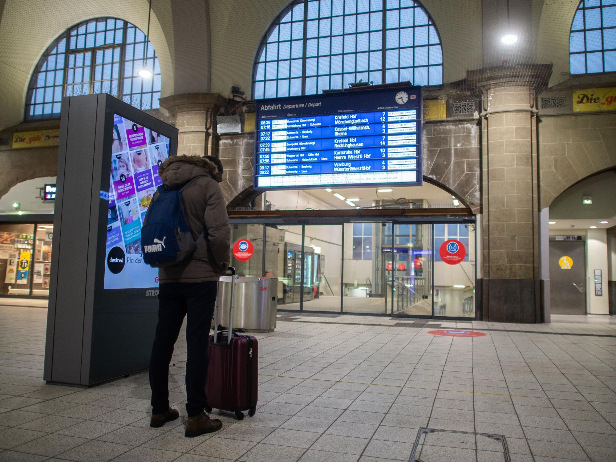 Mann steht im Bahnhof vor einer Anzeigetafel.