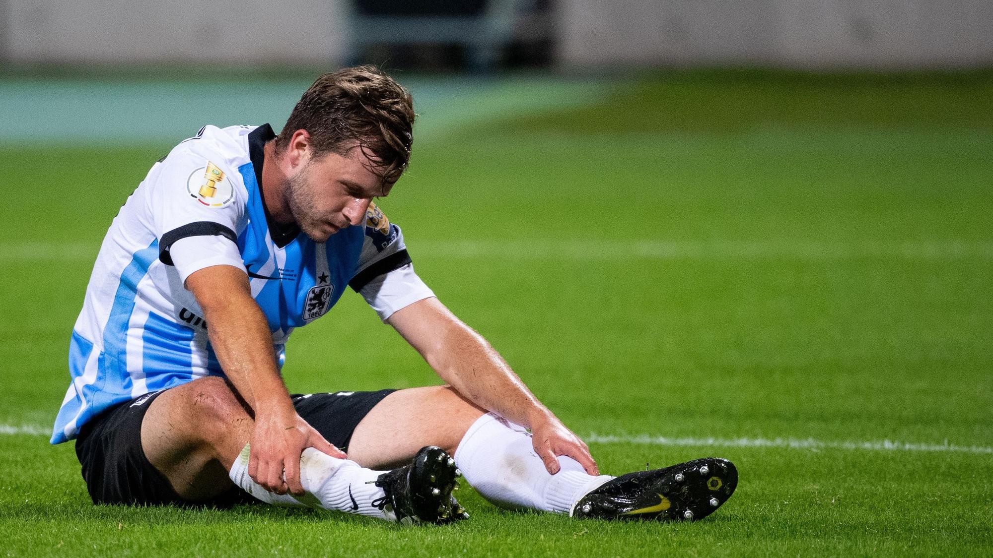 Richard Neudecker sitzt bei einem Spiel von 1860 München auf dem Rasen.