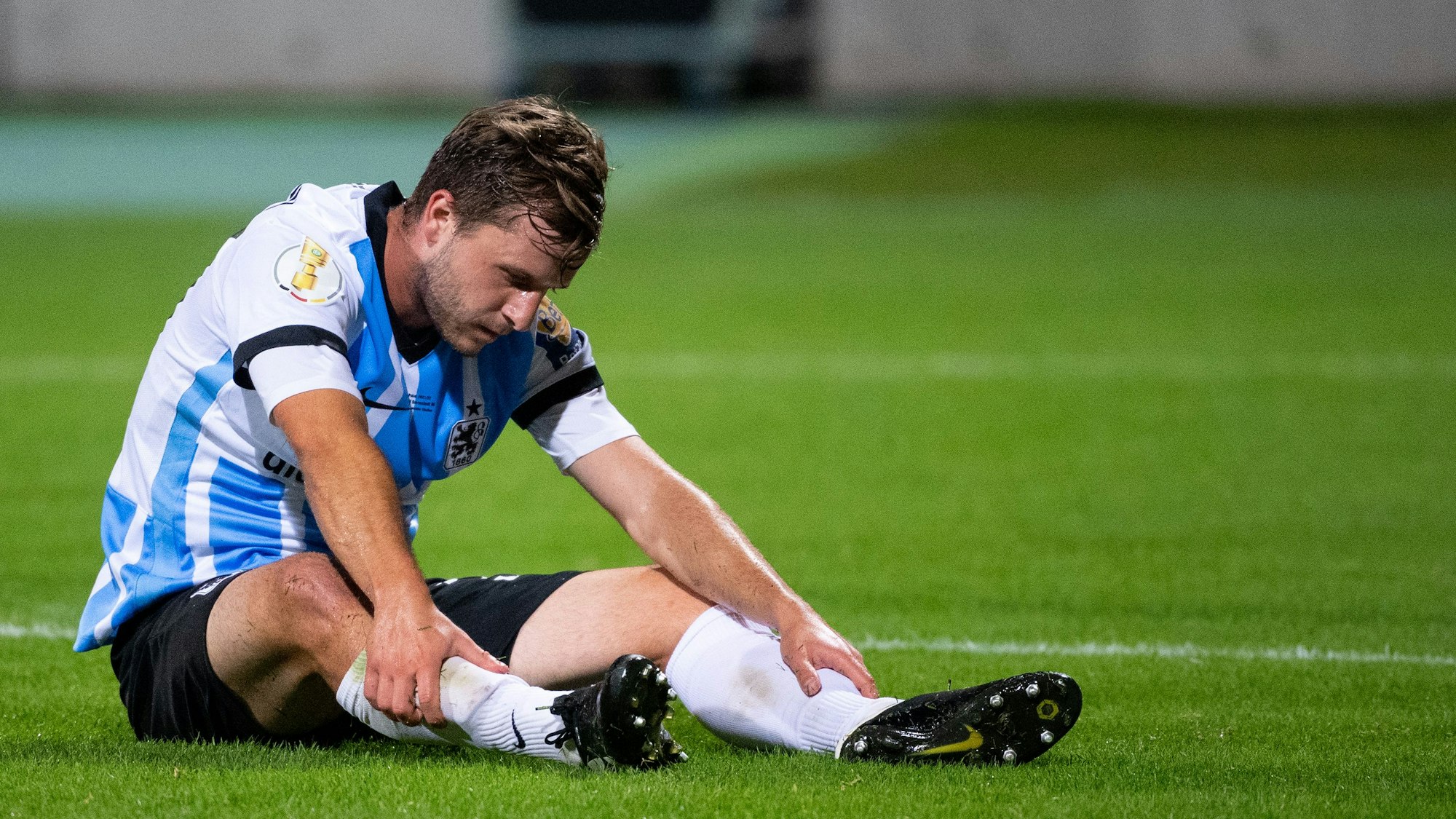 Richard Neudecker sitzt bei einem Spiel von 1860 München auf dem Rasen.