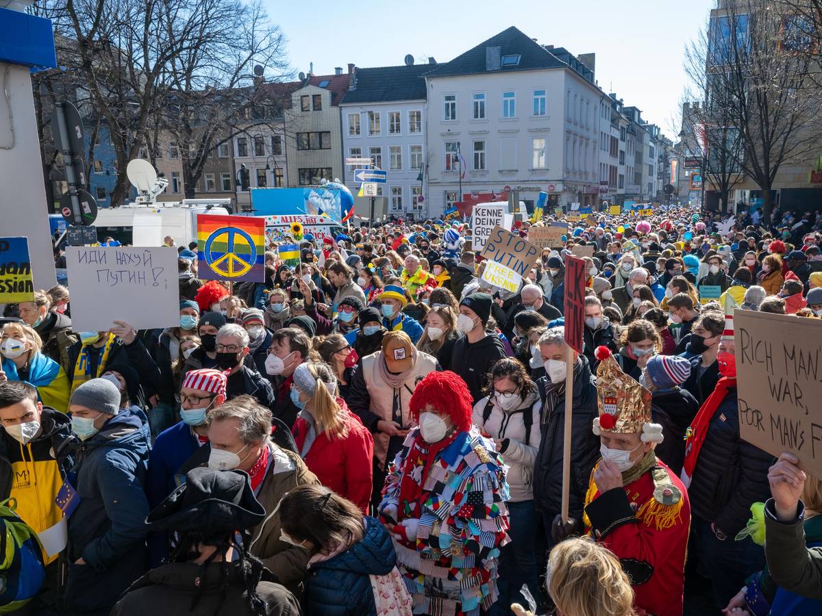Menschen gehen mit der Friedensdemo durch Köln.