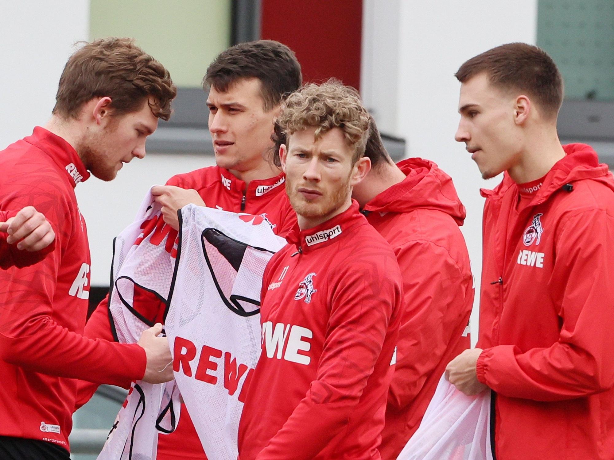 Luca Kilian, Dejan Ljubicic, Florian Kainz und Tim Lemperle ziehen sich beim Training es 1. FC Köln (22. Februar 2022) Leibchen an.