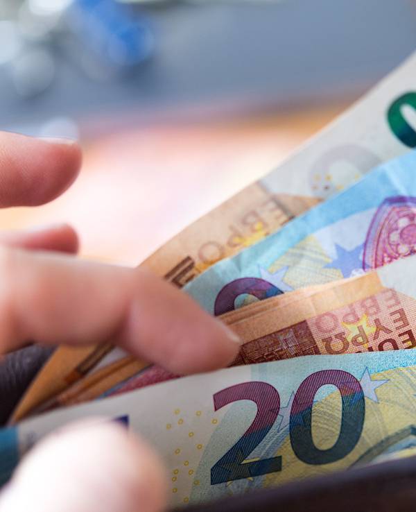Eine Frau hält eine Geldbörse mit Banknoten in der Hand.