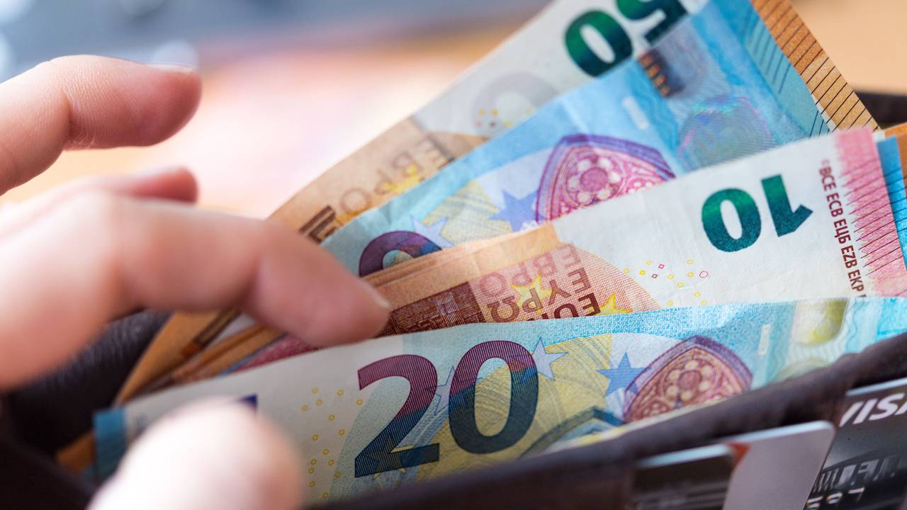 Eine Frau hält eine Geldbörse mit Banknoten in der Hand.
