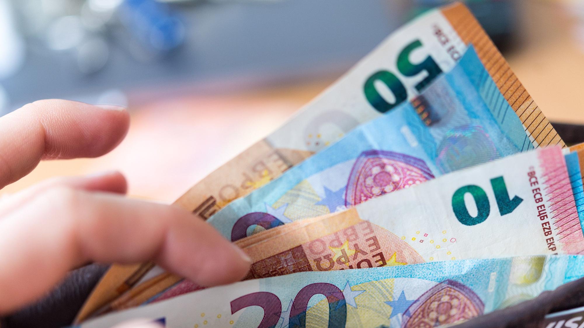 Eine Frau hält eine Geldbörse mit Banknoten in der Hand.