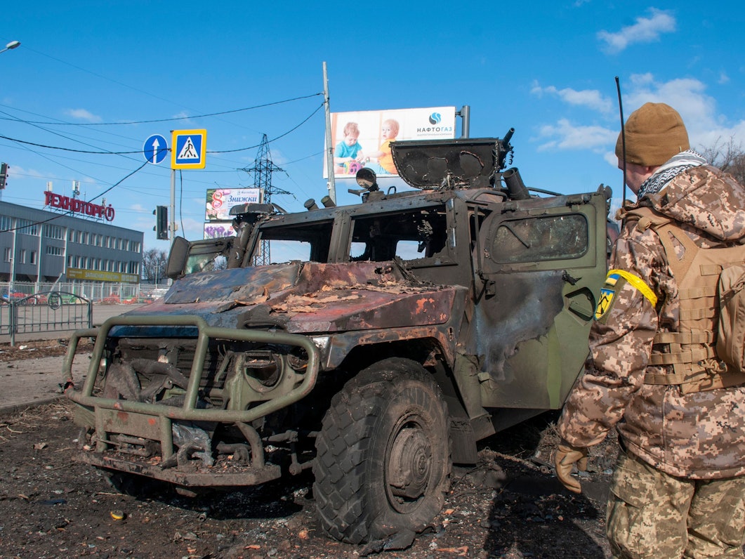 Ein ukrainischer Soldat inspiziert ein beschädigtes Militärfahrzeug.