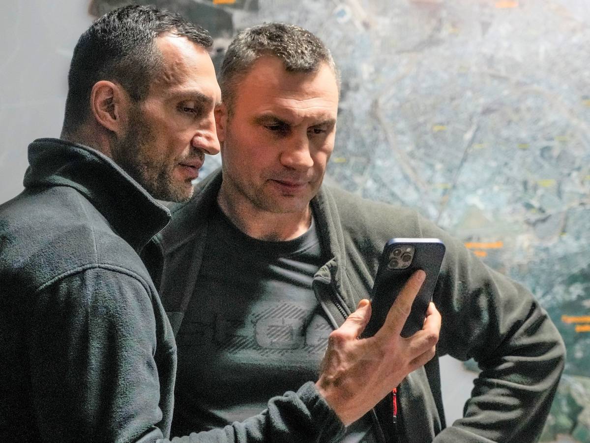 Vitali Klitschko (r), Bürgermeister von Kiew und ehemaliger Box-Profi, und sein Bruder Wladimir Klitschko, ebenfalls ehemaliger Box-Profi, schauen auf ein Smartphone im Rathaus in Kiew.