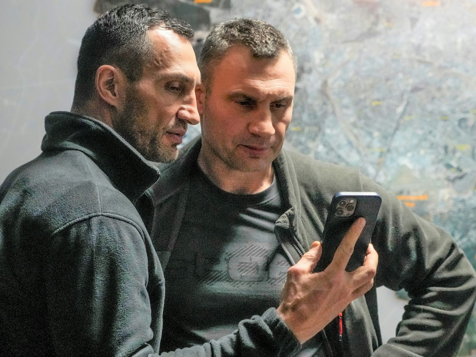 Vitali Klitschko (r), Bürgermeister von Kiew und ehemaliger Box-Profi, und sein Bruder Wladimir Klitschko, ebenfalls ehemaliger Box-Profi, schauen auf ein Smartphone im Rathaus in Kiew.
