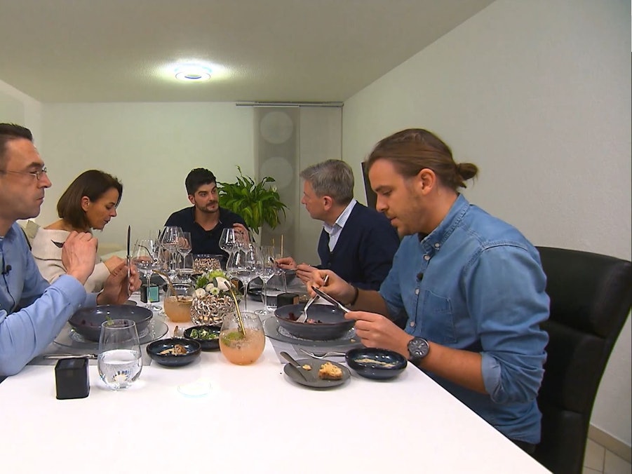 Die „Das perfekte Dinner“-Kandidatinnen und Kandidaten sitzen bei Matthias (m.) am Esstisch.